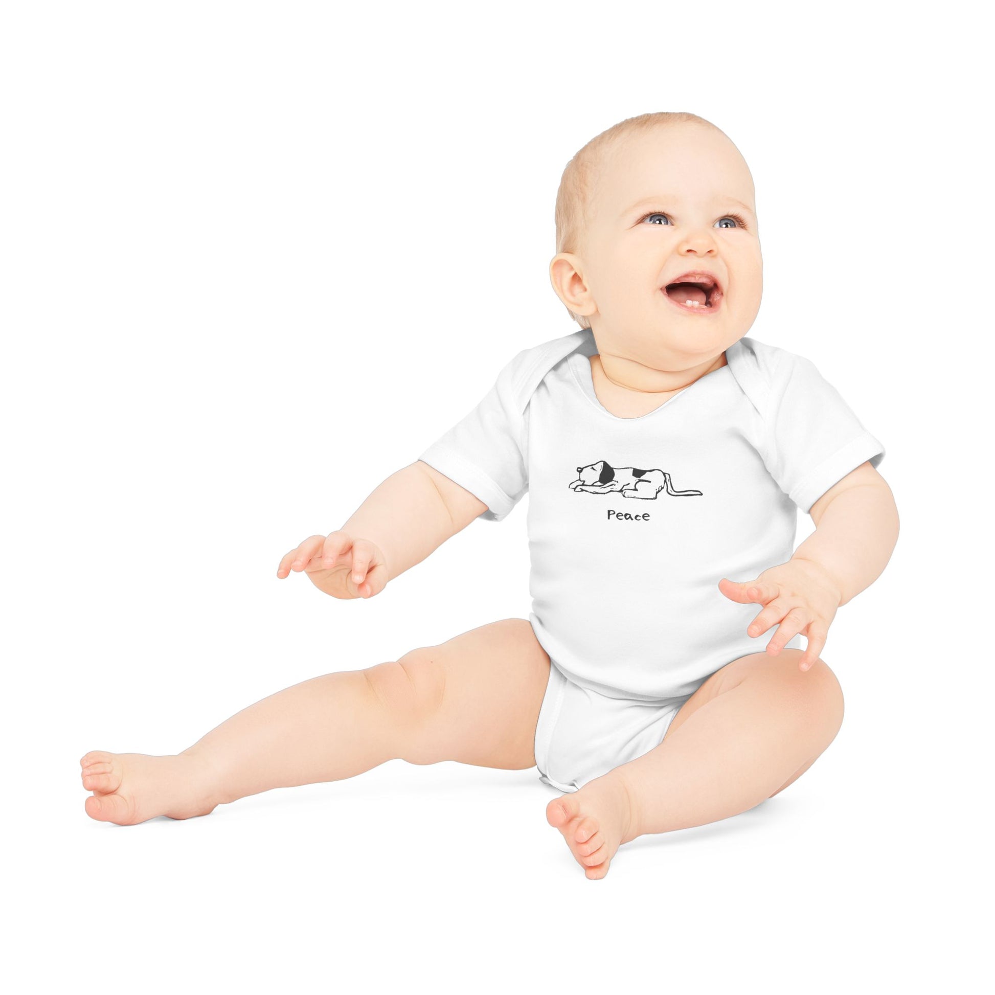 White short-sleeve onesie baby bodysuit on a smiling baby sitting up with arm outstretched in front, with head turned and looing up. Onesie features a simple black and white illustration of a sleeping dog above the word "Peace" printed on the chest.
