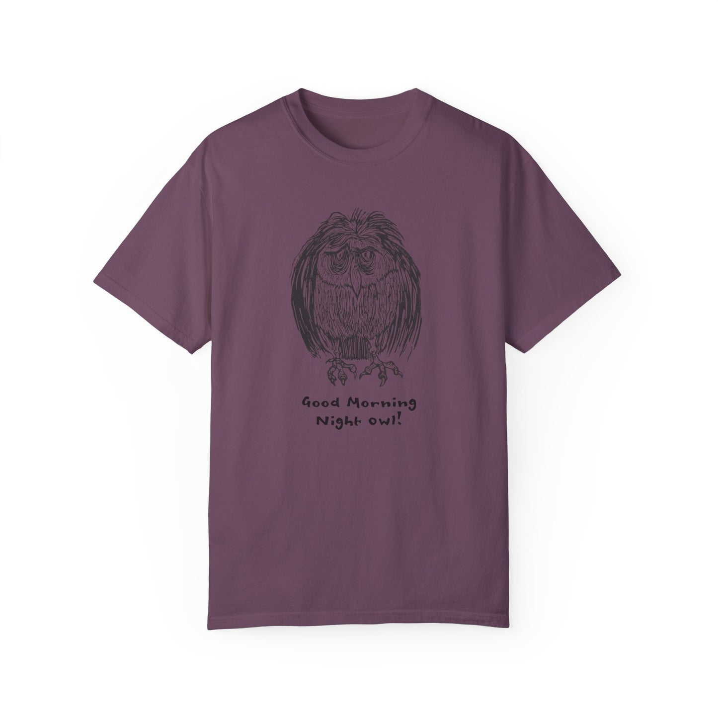 Dark purple colored t-shirt featuring an illustration of a tired-looking owl with messy feathers, created from a linoleum block print. The owl stands with drooping eyes, and below it, the text reads: “Good Morning Night Owl!