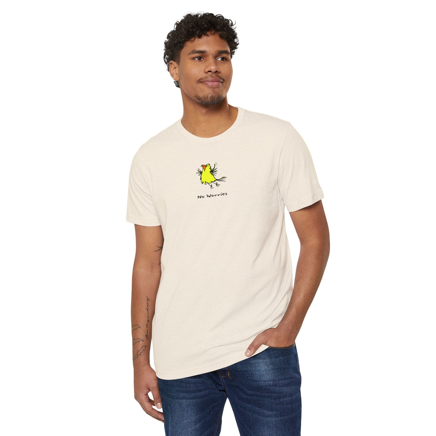 Man wearing a white t-shirt featuring a small, centered linocut-style illustration of a happy looking flying yellow bird with an orange beak.  Below the artwork is the phrase “No Worries.”