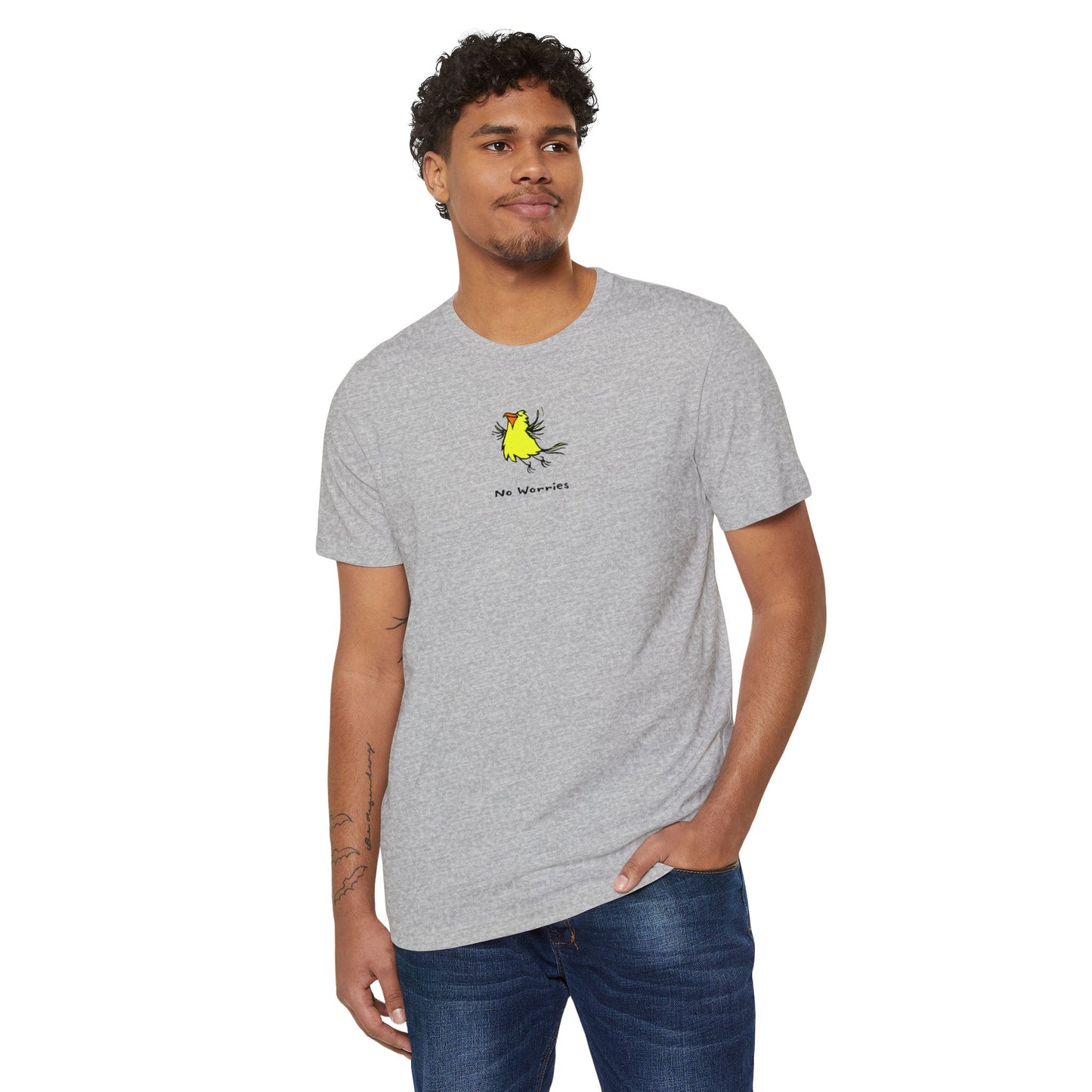 Man wearing a heather gray t-shirt featuring a small, centered linocut-style illustration of a happy looking flying yellow bird with an orange beak.  Below the artwork is the phrase “No Worries.”