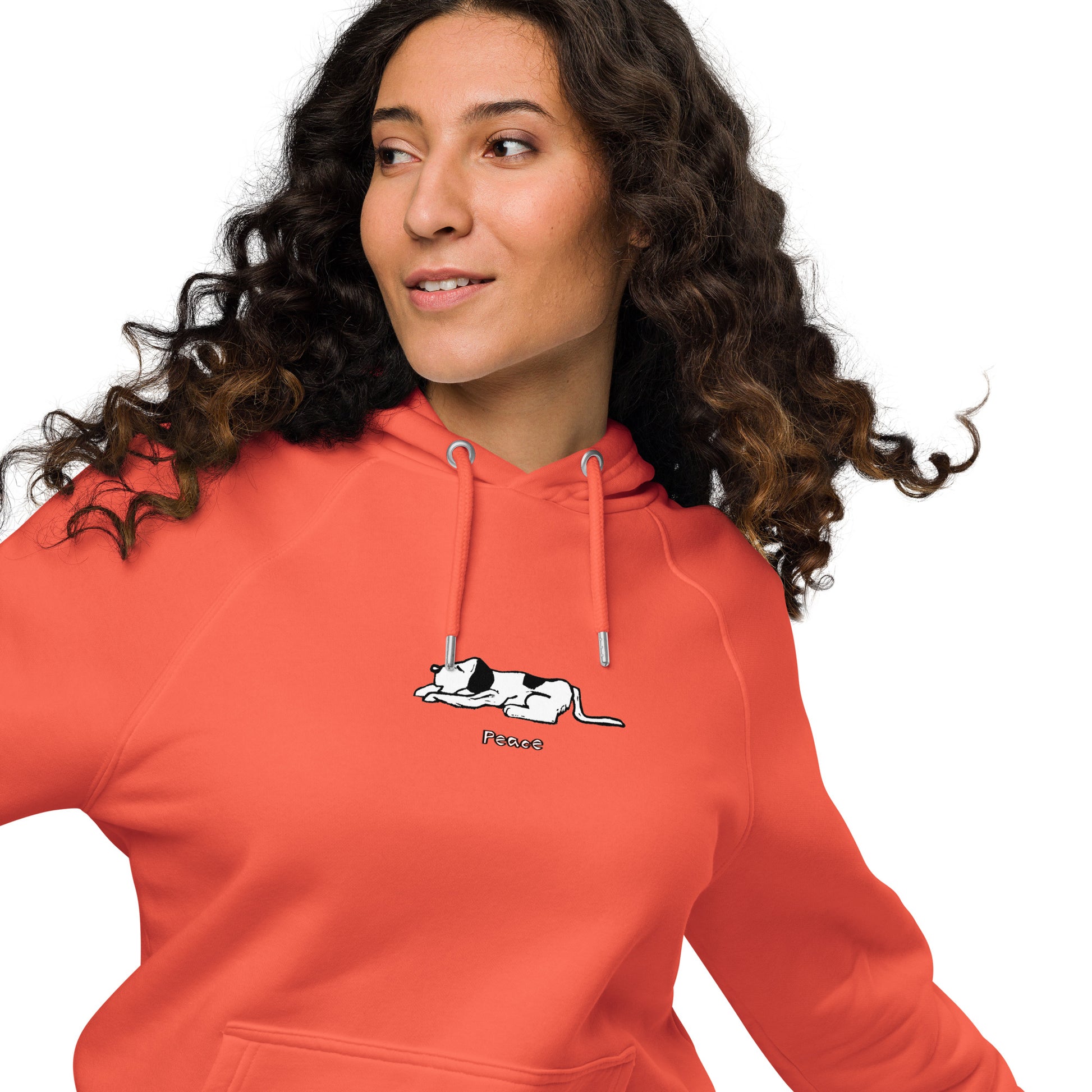 Woman wearing a orange hoodie featuring a black and white illustration of dog lying down with its eyes closed.  The word “Peace” printed beneath the design.